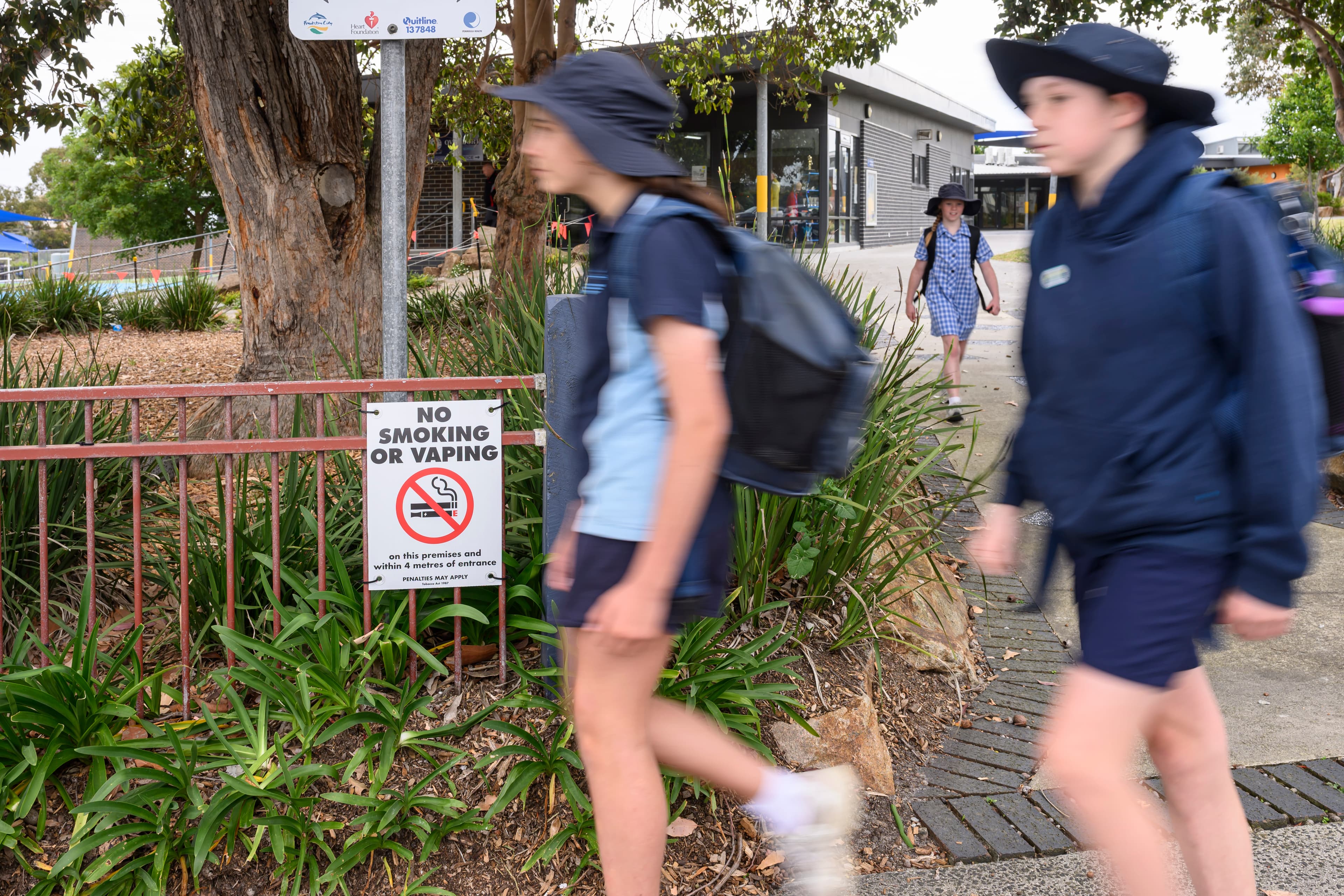 Two students walking past a no smoking or vaping sign